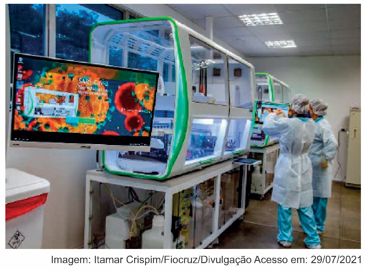 Fotografia de um laboratório da Fiocruz com grandes equipamentos automatizados de testagem em bancadas. À esquerda, um monitor exibe a imagem microscópica do vírus SARS-CoV-2 em tons de laranja e vermelho. À direita, duas profissionais vestindo aventais descartáveis, toucas e luvas operam um dos equipamentos. Crédito da imagem: Itamar Crispim/Fiocruz/Divulgação. Acesso em: 29/07/2021.
